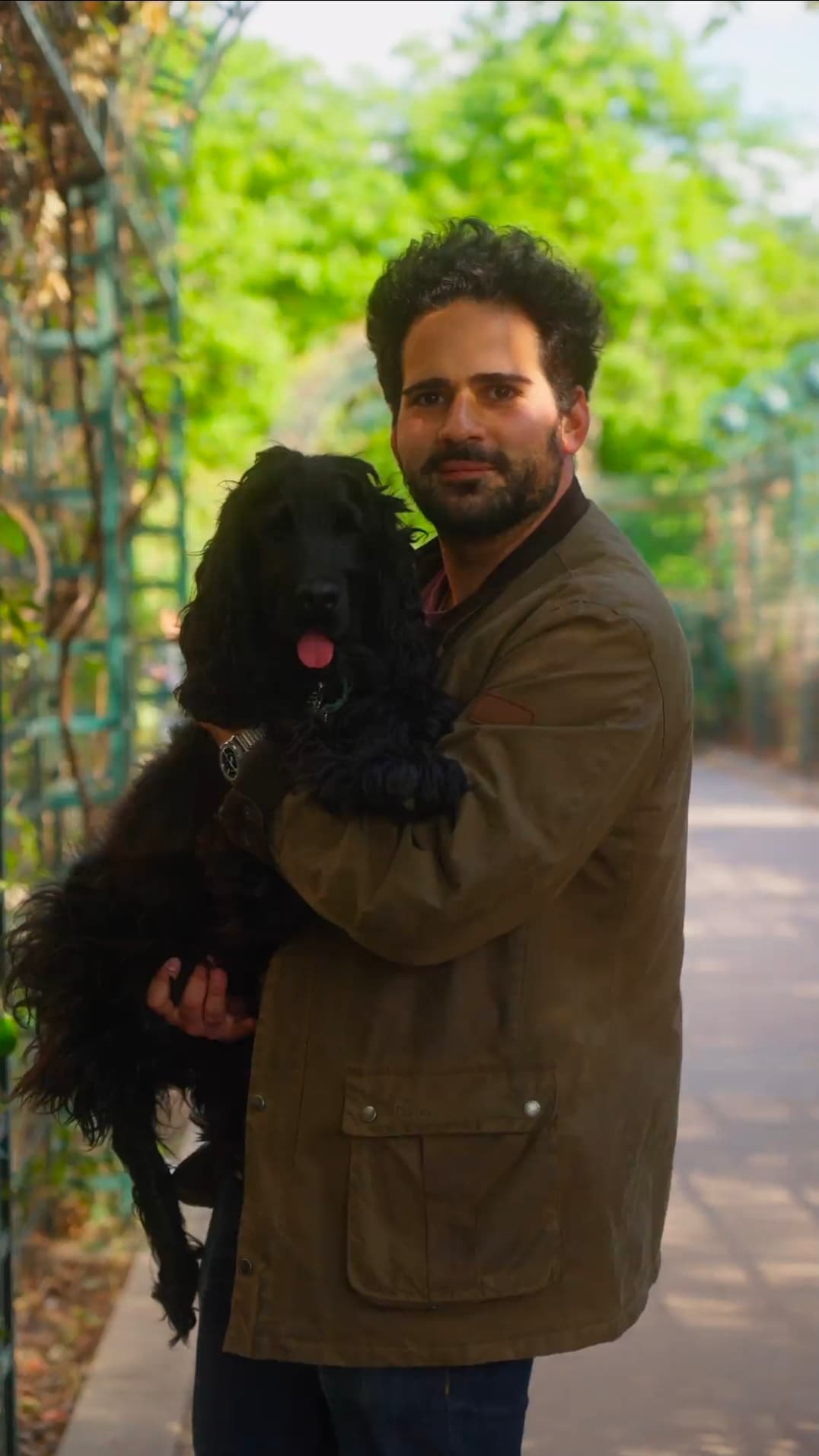 Léo Bentolila, œnologue et fondateur de Parlez-moi de Vin, portant son chien noir dans une allée ombragée